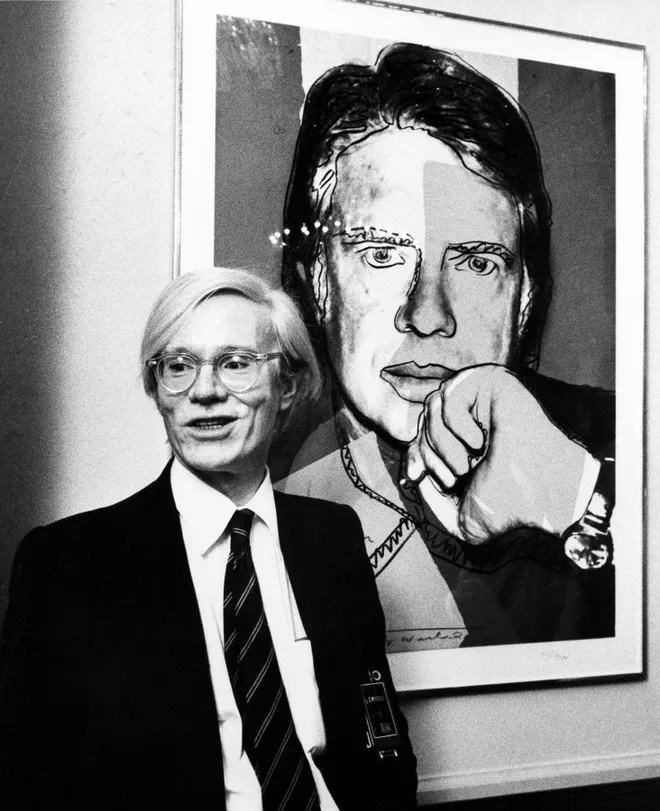 Andy Warhol standing infront of his Jimmy Carter screenprint