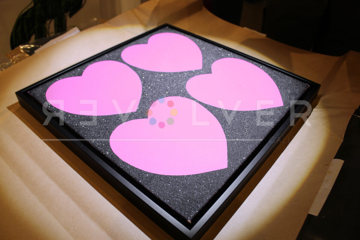 Warhol's Four Hearts painting in a frame with light illuminating the diamond dust sparkles.