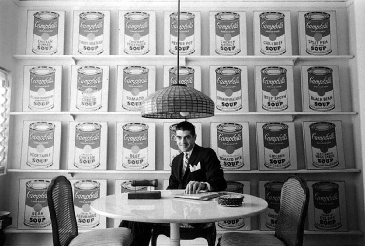 Gallerist Irving BLum sitting infront of Warhol's Souo Cans.
