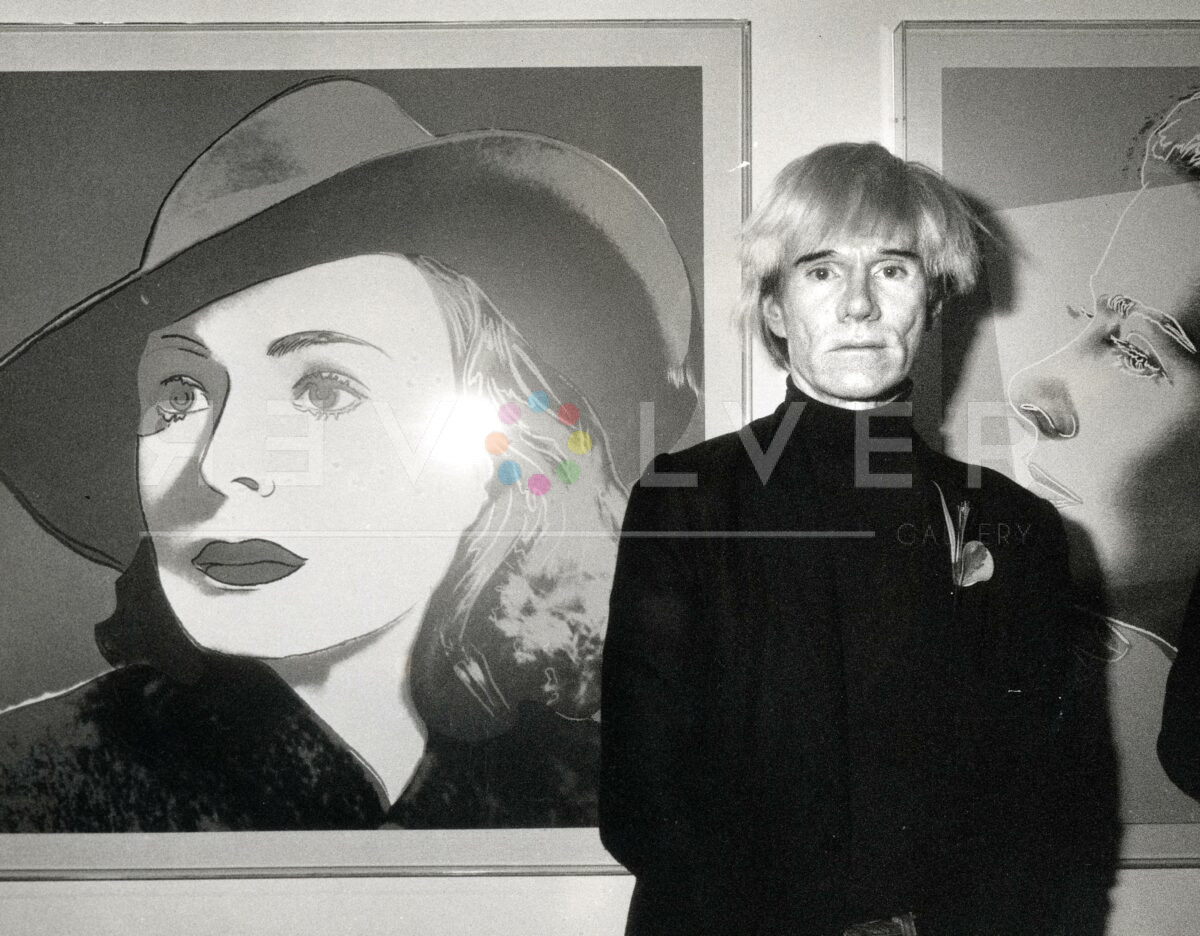 Andy Warhol standing in front of his Ingrid Bergman with Hat screen print.