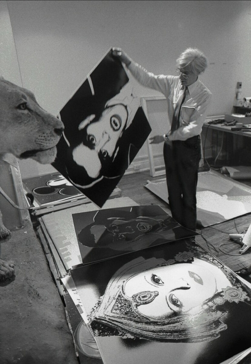 Andy Warhol in his studio holding the Dracula screenprint from Myths