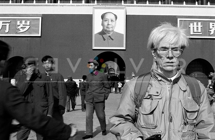 Andy Warhol visiting China in 1982, posing in front of Chairman Mao's portrait.