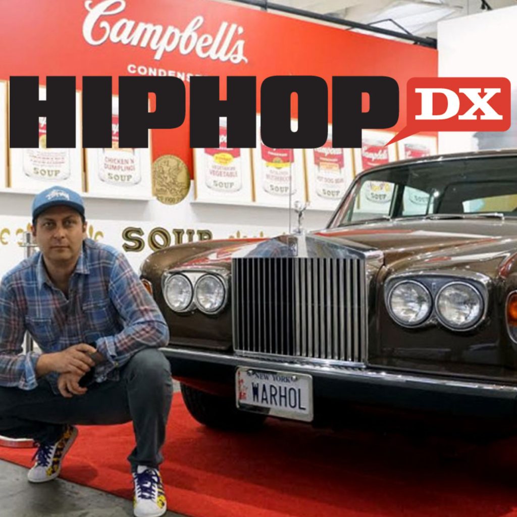 Ron Rivlin crouching in front of Andy Warhol's Rolls Royce for HIPHOPDX: Ron Rivlin Went From Booking Rap Acts To Andy Warhol Collector, 2019, stock version.