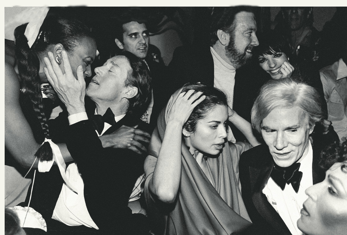 Fashion designer Halston and Andy Warhol amidst the boisterous crowd at Studio 54 night club.