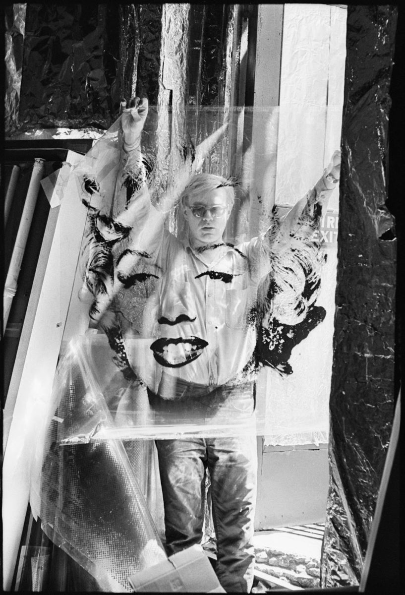 Andy Warhol holds up a transparent Marilyn Monroe screen during the printing process.