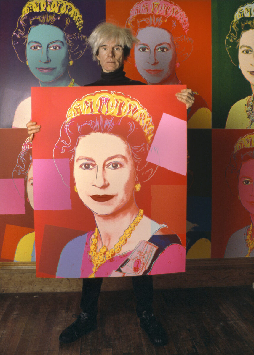 Andy Warhol holding one of his Queen Elizabeth II screenprints.