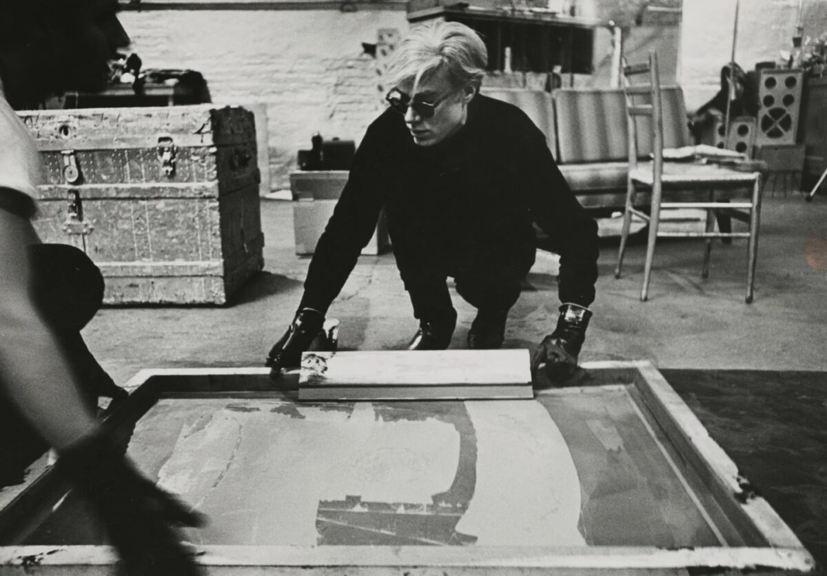 Andy Warhol at work on a silkscreen painting. 1964, The Silver Factory By Ugo Mulas.