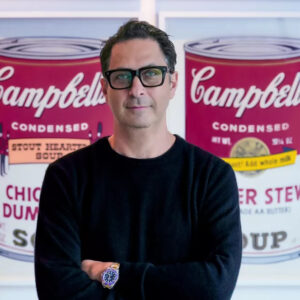 Revolver Gallery owner Ron Rivlin poses for a portrait in front of Warhol's Campbell's Soup prints.