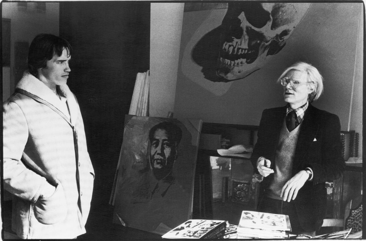 Arnold Schwarzenneger and Andy Warhol speaking together in the Factory.